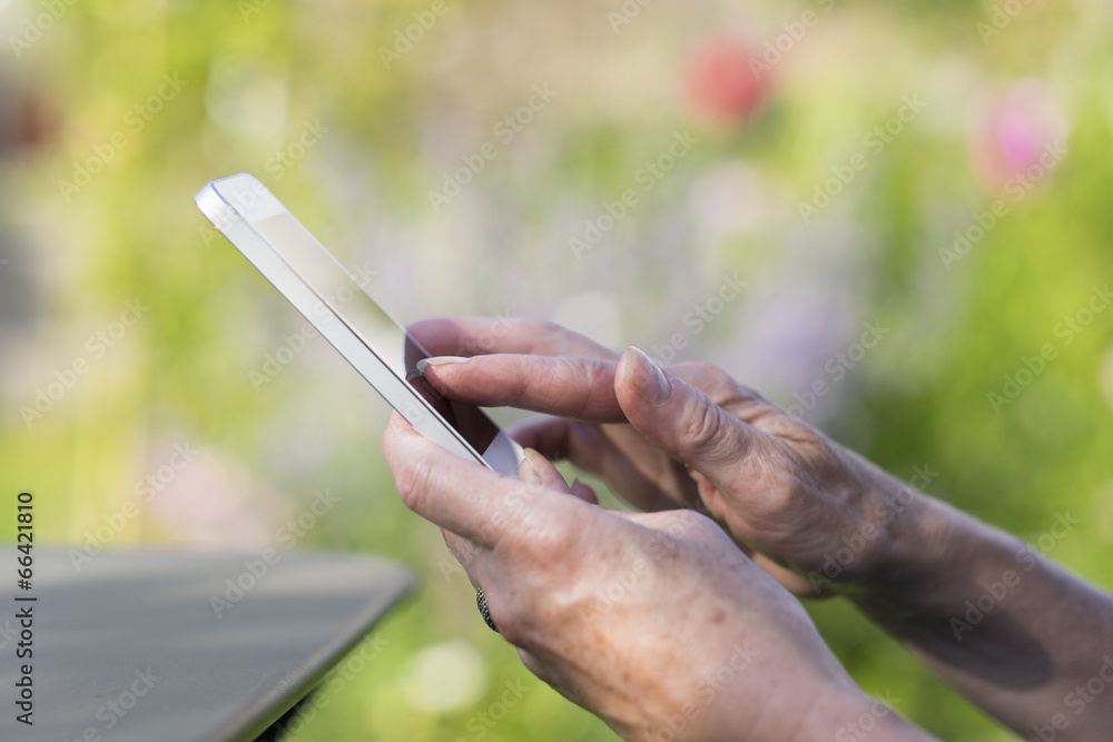 Woman Senior using a mobile phone in garden
