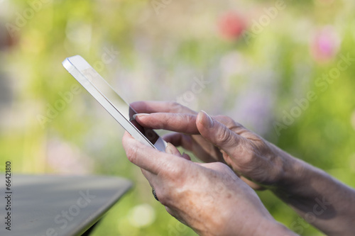 Woman Senior using a mobile phone in garden