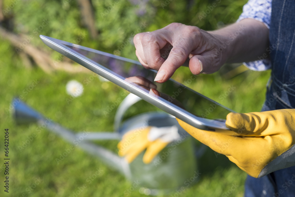 Gardening woman senior using a digital tablet computer in garden Gardening woman senior using a digital tablet computer in garden