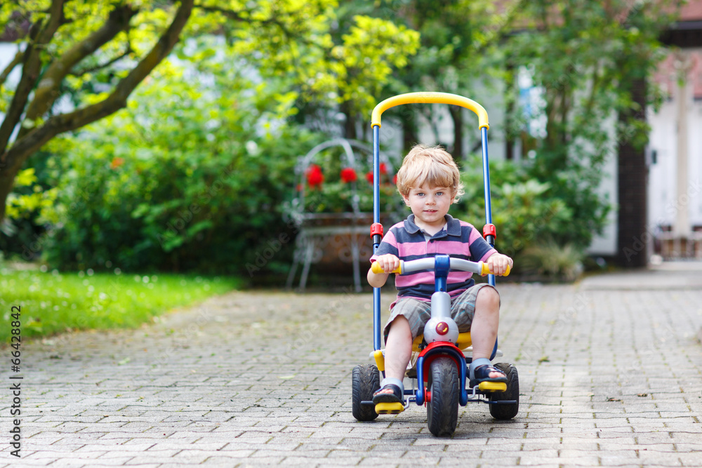 Little toddler driving tricycle or bicycle in home garden Little toddler driving tricycle or bicycle in home garden