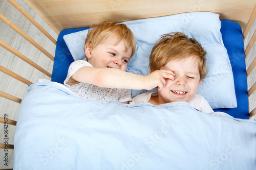 little sibling boys having fun in bed at home