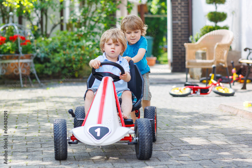 Two happy sibling boys having fun with toy car Two happy sibling boys having fun with toy car