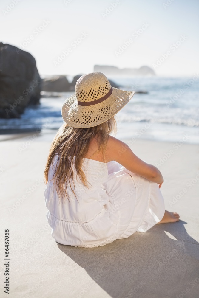 Beautiful blonde in sundress sitting on the beach