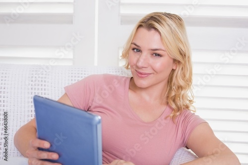 Happy blonde relaxing on the couch with tablet pc