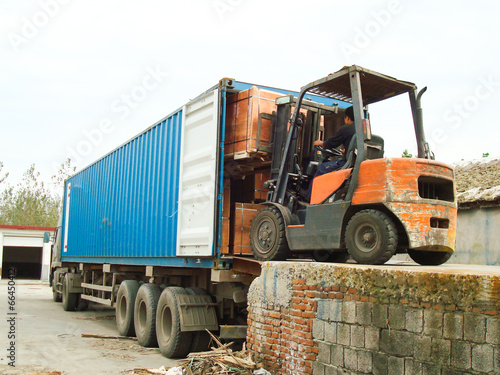 Electric Forklift Loading Cargos into Container