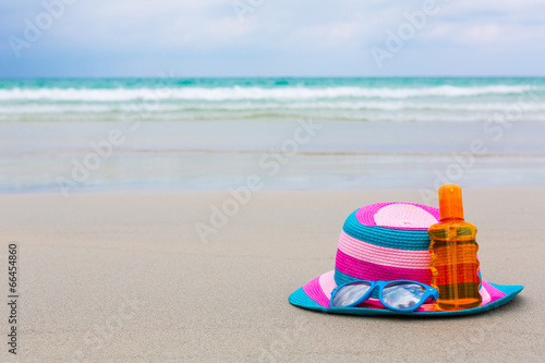 Sunscreen lotion and dark glasses with hat on the beach for summ