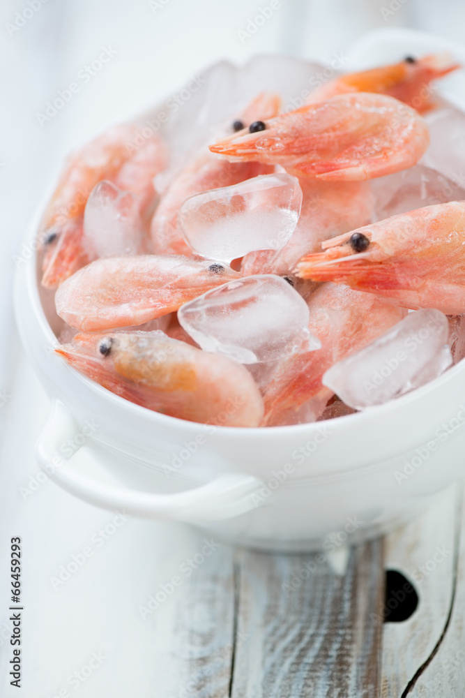 Glass bowl with raw shrimps on ice, close-up, vertical shot Glass bowl with raw shrimps on ice, close-up, vertical shot