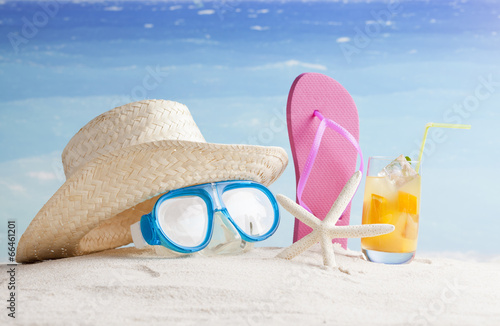 Straw hat,  snorkel mask and flip flops on a tropical beach 