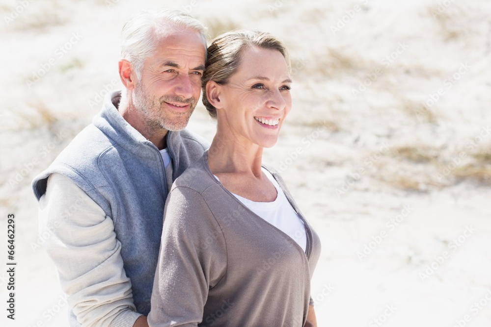 Happy hugging couple on the beach looking away Happy hugging couple on the beach looking away
