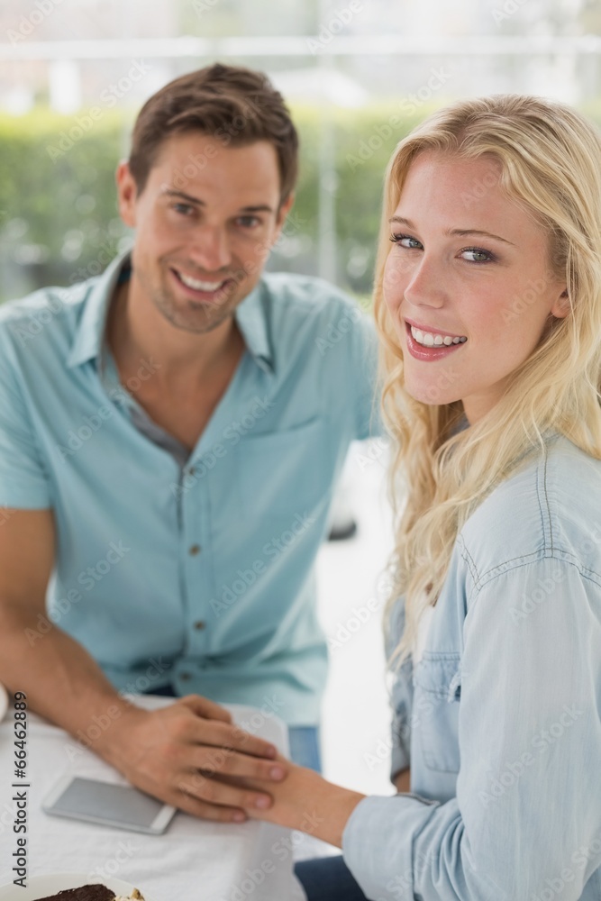 Hip young couple sitting at table smiling at camera Hip young couple sitting at table smiling at camera