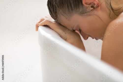 Stressed young woman sitting in bathtub