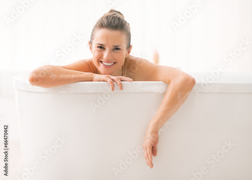 Young woman looking out from bathtub