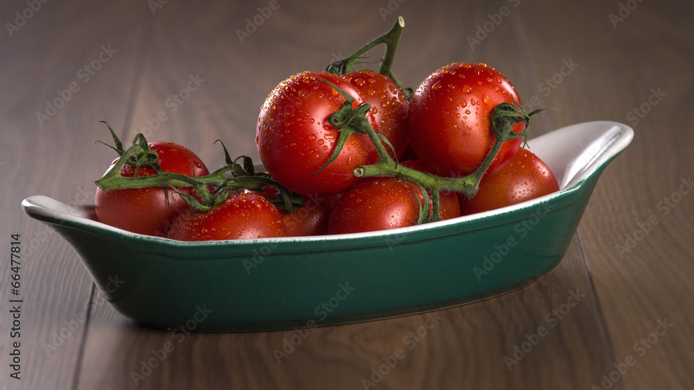 Ripe cherry tomatoes in a bowl on a wooden table