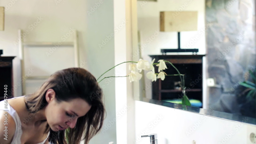 Woman applying makeup, powder on her face in the bathroom Woman applying makeup, powder on her face in the bathroom