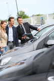 Car dealer showing vehicles to couple