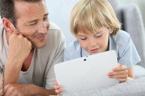 Man with little boy playing with digital tablet