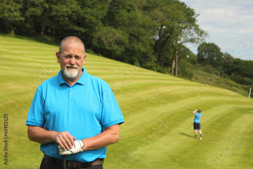 A golfer with another golfer in the background