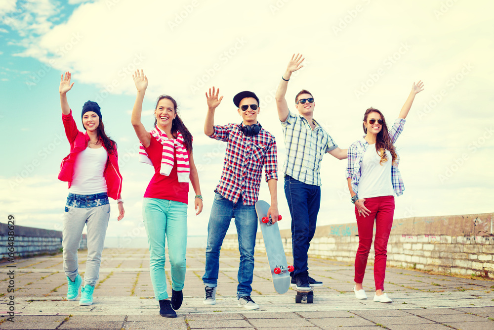 Obraz premium group of smiling teenagers waving hands