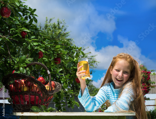 Tableau sur toile Girl in apple orchard drinks juice