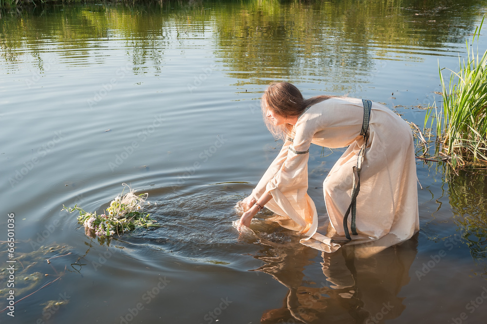 Beautiful girl lowers wreath in water Beautiful girl lowers wreath in water