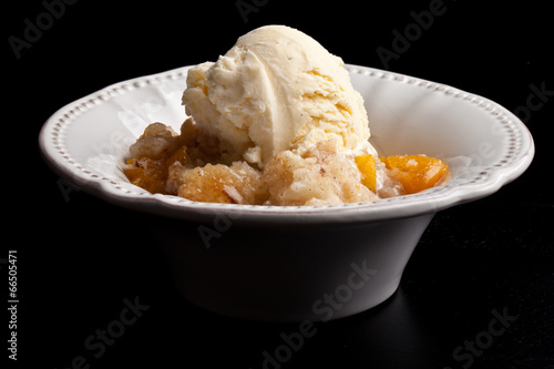 Canvas Print Homemade peach cobbler crisp in an antique white vintage bowl topped with vanill