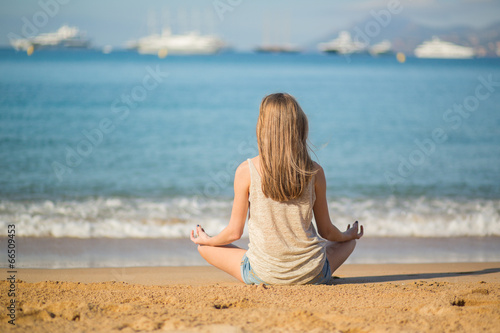 Young woman meditating on the beach