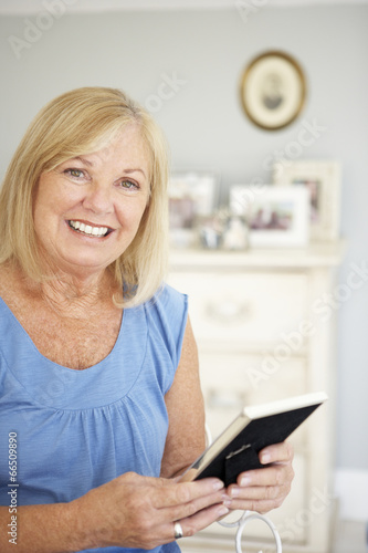 Senior woman with photographs at home