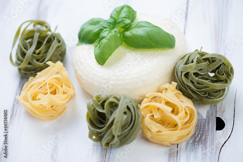 Close-up of cheese with green basil and coloured tagliatelle