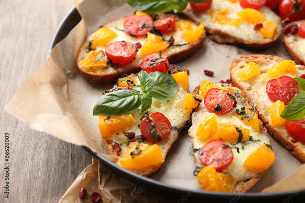 Tasty bruschetta with tomatoes on pan, on old wooden table Tasty bruschetta with tomatoes on pan, on old wooden table