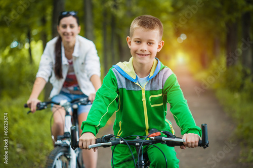 Happy family. mother and son riding bicycle in the park