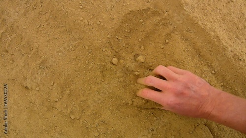 Pink skin hand looking for something in extremely dry dusty clay photo