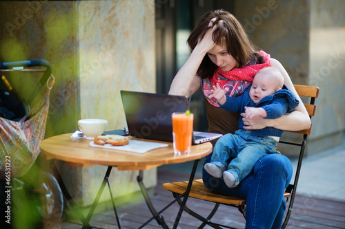 Tired young mother working oh her laptop photo