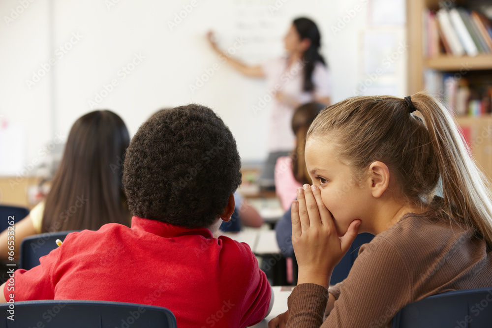 Schoolchildren whispering in class Schoolchildren whispering in class