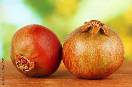 unripe pomegranates on green background close-up