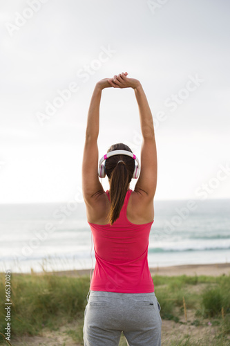 Fitness female athlete stretching arms towards the sea