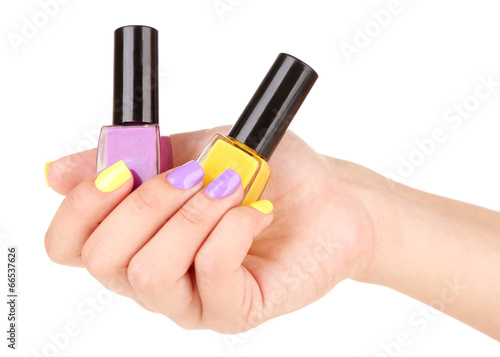 Female hand with stylish colorful nails holding bottle with