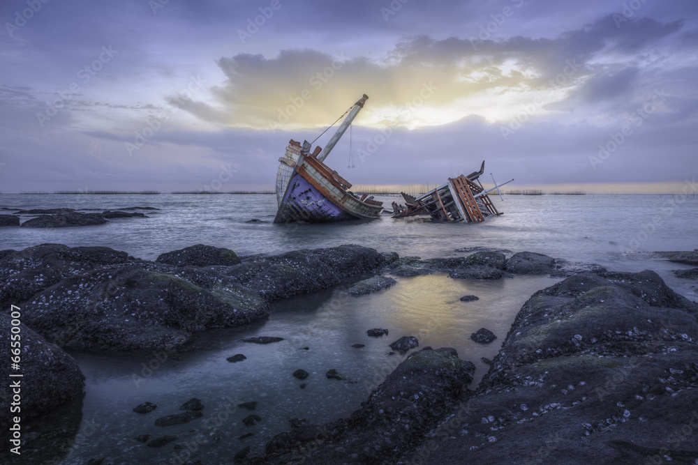 Shipwreck or wood ship broken damage on land, coast or beach with sea and sunset background. That result of accident, storm, crash, wave in ocean or marine. For assurance, travel or adventure concept. Shipwreck or wood ship broken damage on land, coast or beach with sea and sunset background. That result of accident, storm, crash, wave in ocean or marine. For assurance, travel or adventure concept.