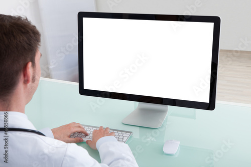 Confident Male Doctor Working On Computer At Desk