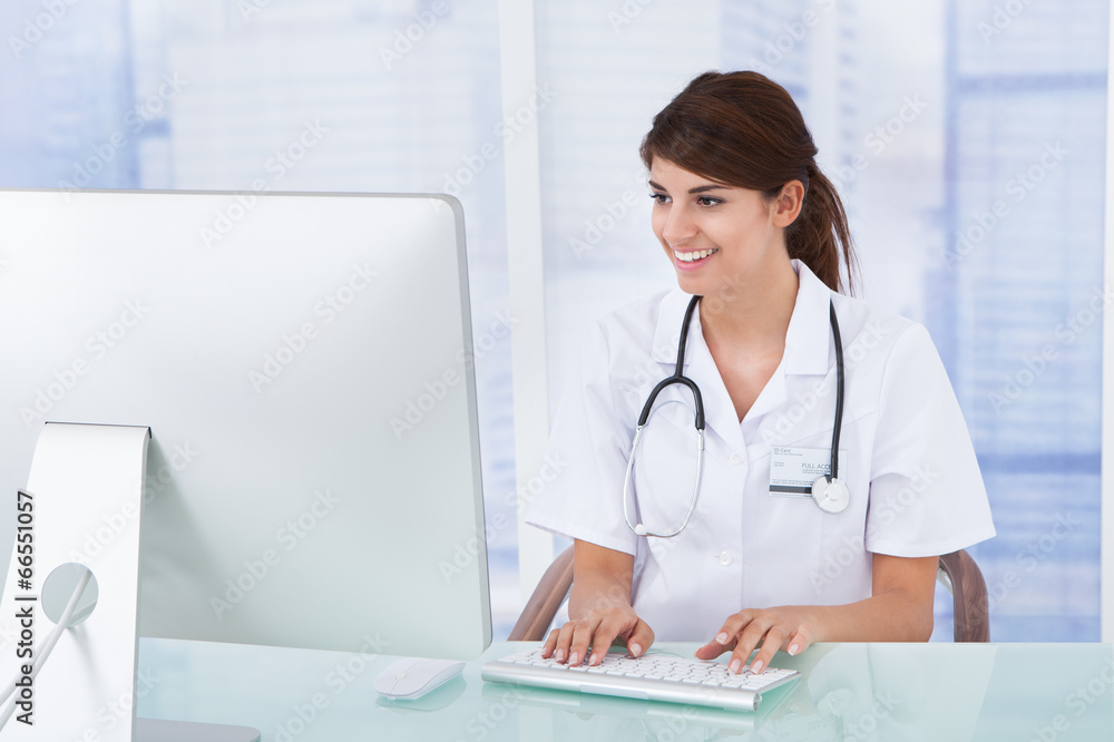 Doctor Using Computer At Desk In Clinic Doctor Using Computer At Desk In Clinic