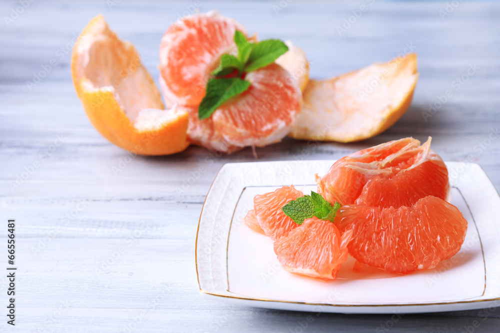 Ripe peeled grapefruits on plate, on color wooden background Ripe peeled grapefruits on plate, on color wooden background