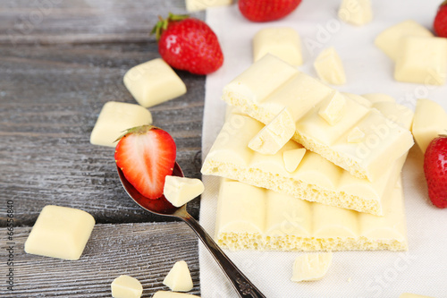 Fotografie White broken chocolate bar on napkin on color wooden background