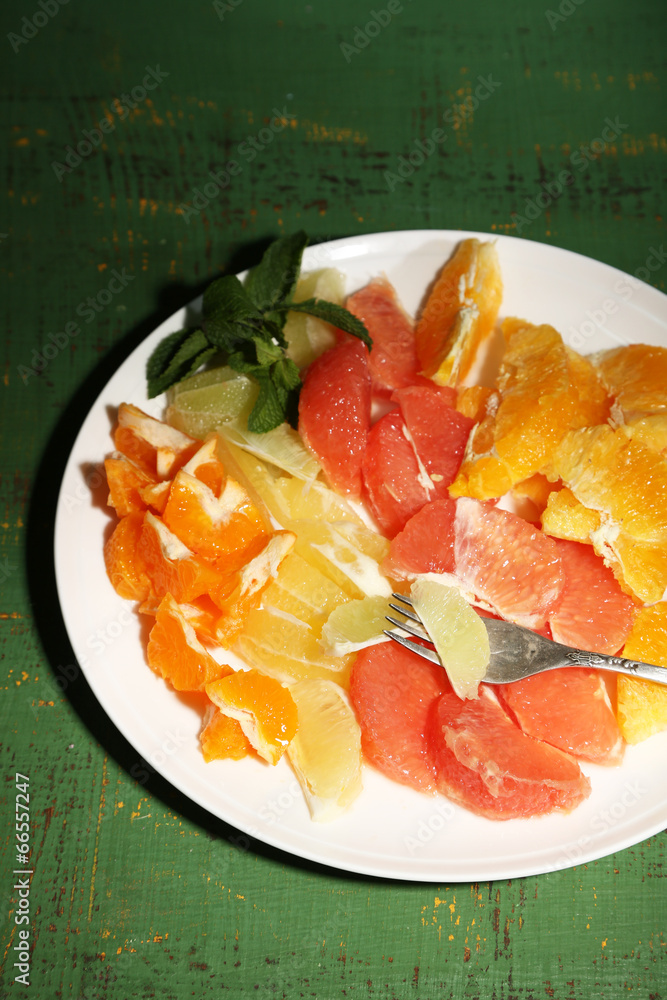 Sliced citrus fruits on plate, on wooden background Sliced citrus fruits on plate, on wooden background