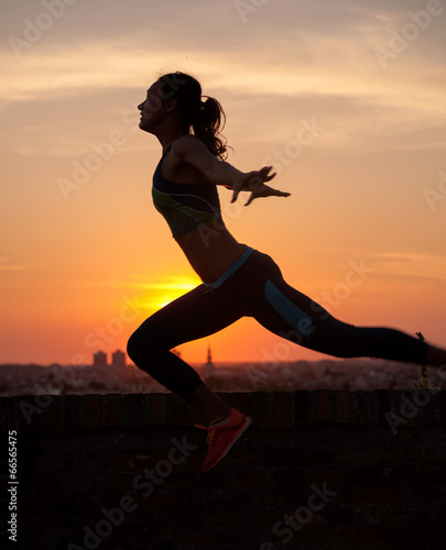 Fototapeta Naklejka Na Ścianę i Meble -  Silhouette of Girl streching at Sunrise or Sunset