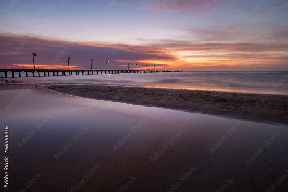 Smooth water surface and pier in orange sunset  colors