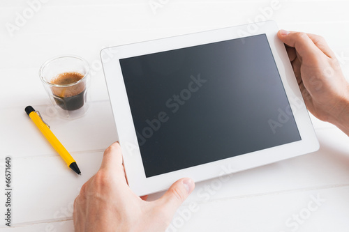 Hands of a man holding blank tablet device over wooden table