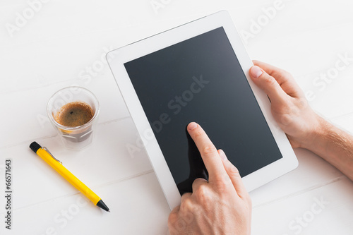 Hands of a man holding blank tablet device over wooden table