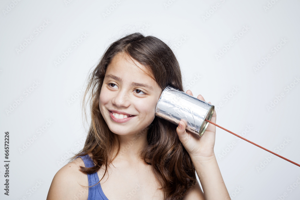 Happy smiling child using a can as telephone against gray backgr Happy smiling child using a can as telephone against gray backgr