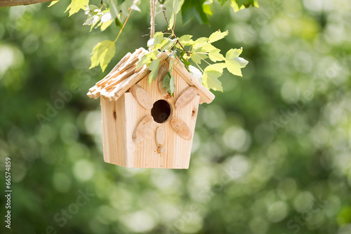 New Wooden Birdhouse hanging on tree branch outdoors