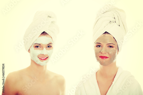 Young happy women with facial clay mask