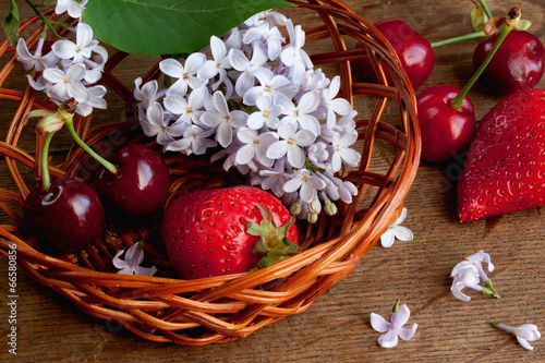 strawberries and cherries in a basket on the wooden surface